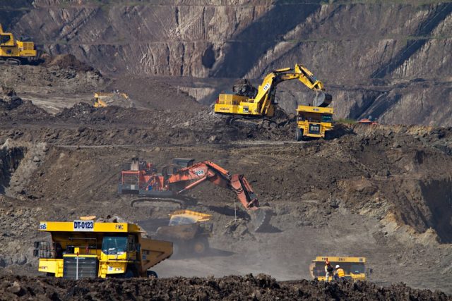 BMA sells Blackwater and Daunia mines to Whitehaven Coal in April 2024 Whitehaven Coal trucks load at Blackwater pit while BMA sign comes down under cloudy Queensland sky.