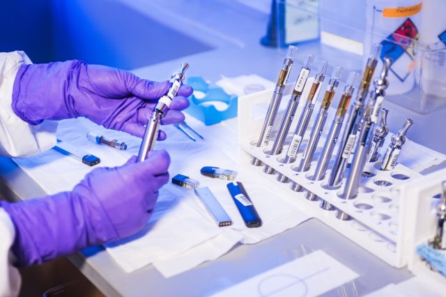 Bahrain Becomes Second Country to Approve DNA-Rewriting Therapy Casgevy A scientist holds a vial of Casgevy gene-editing therapy in a lab with CRISPR equipment in the background.