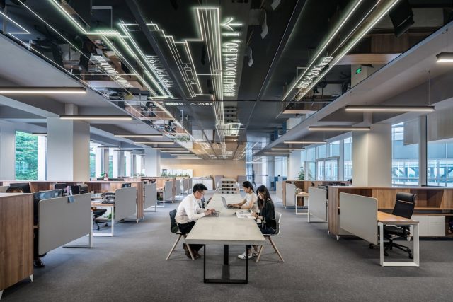 Game Industry's Post-Pandemic Hiring Boom Reverses Into Mass Layoffs Rows of empty desks in a darkened game studio with monitors showing canceled project logos