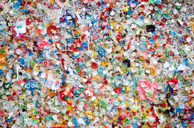 Plastic Ban Takes Effect But Faces Challenge from Unconstitutional Ruling A person holding a reusable shopping bag at a grocery store, with plastic straws and cutlery visible in a bin nearby