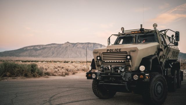 Kata'ib Hezbollah Suspends US Attacks to Avoid Embarrassing Iraqi Government Armed militia members in uniform stand near military vehicles in Iraq, representing Kata'ib Hezbollah's state-sanctioned brigades.