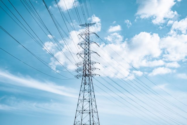NGCP Consortium Controls Power Restoration to Five Central Philippine Islands A power transmission tower on a Philippine island with lights flickering on in the background after a blackout.
