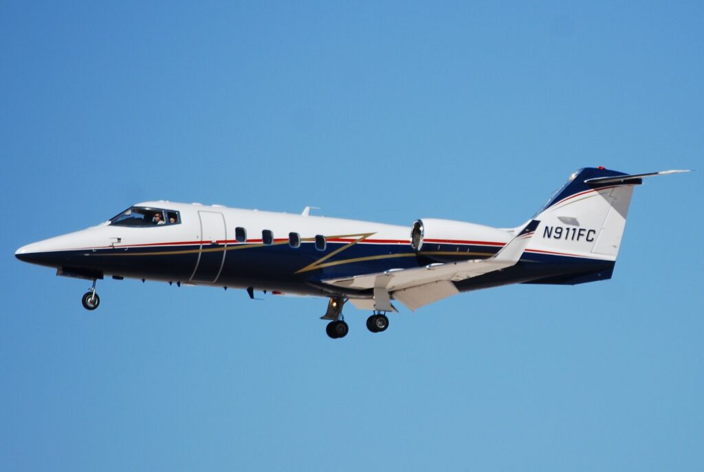 Emergency responders at the scene of a Learjet 55 crash in a Philadelphia neighborhood, with damaged homes and debris visible.