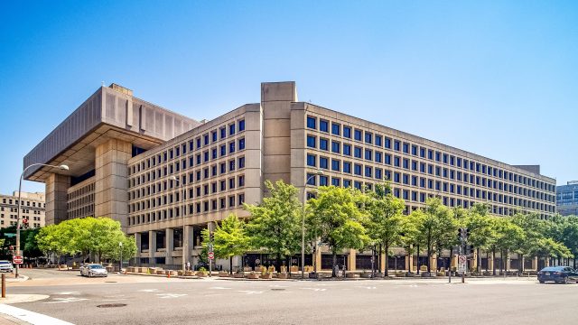 Fbi Headquarters J Edgar Hoover Building A grainy monochrome image with a central crosshair reticle shows a small dark circular object below the center against an indistinct mountain range background.