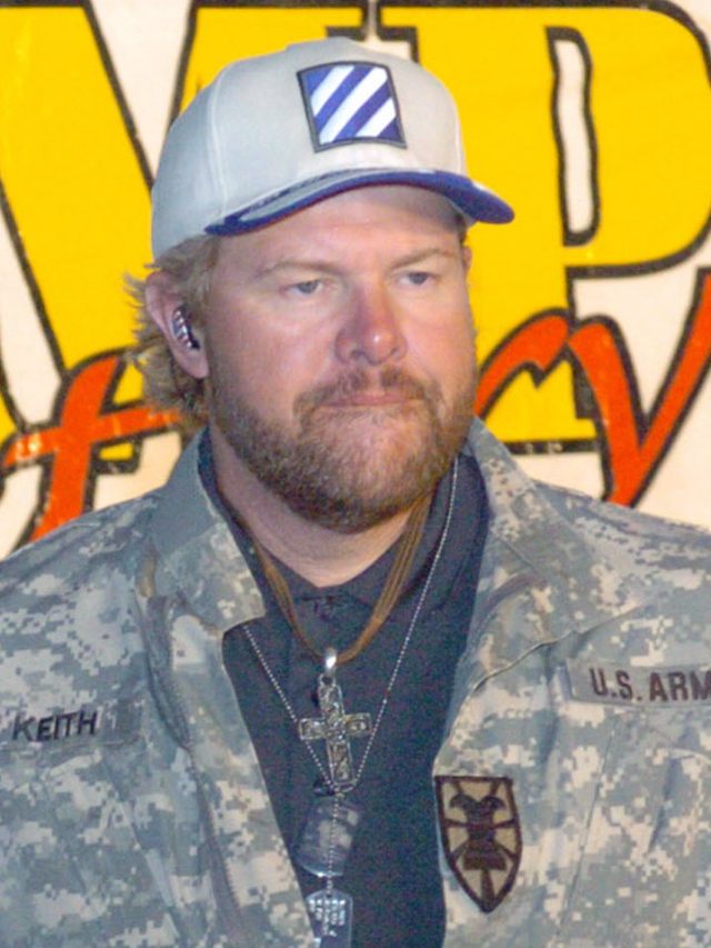 Peso in My Pocket Toby Keith performing on stage with a guitar, smiling at the audience during a concert.