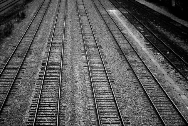 Seven Migrants Found Dead at Two Texas Rail Sites in May 2026 A sealed train boxcar sits on tracks in a Texas rail yard, surrounded by emergency vehicles and investigators.